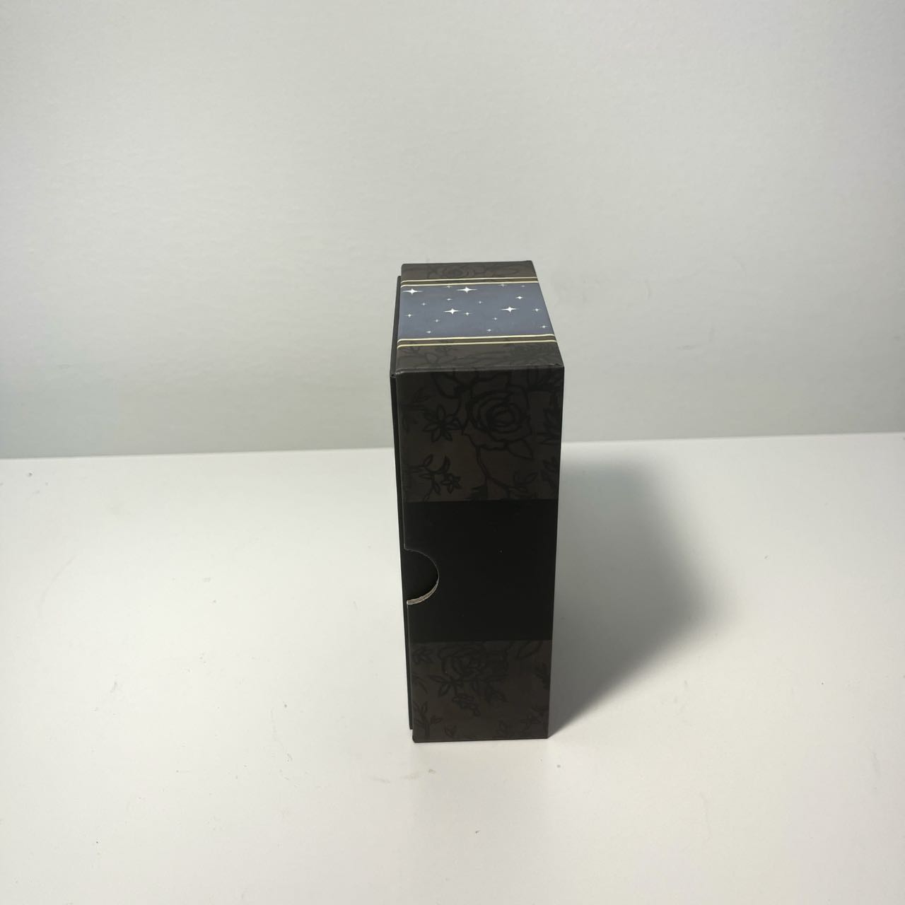 Rectangular box standing upright on a tabletop, photographed from the side